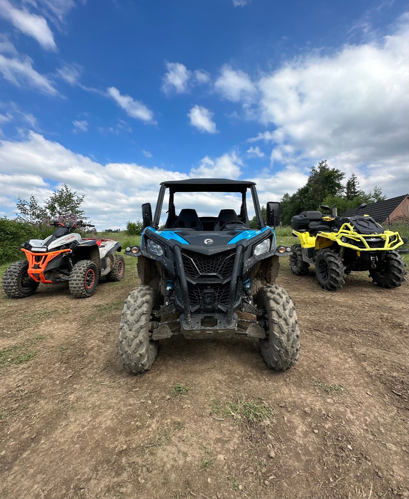 Three buggies, orange, blue and yellow, on a dirt track under a blue sky